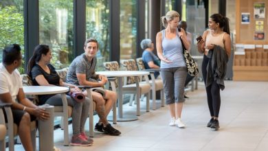 Two women walk through the annex of a gym and joyfully greet the people they see.