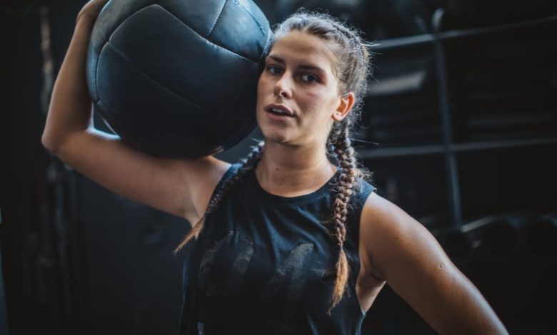 Athlete woman in gym practicing cross training with medicine ball