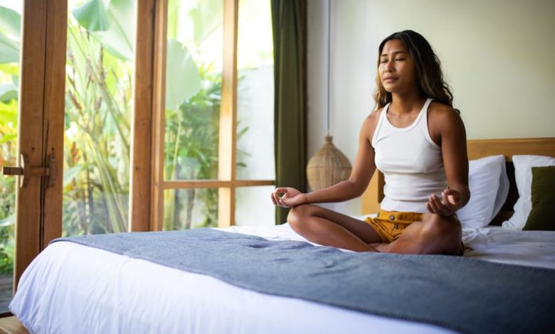 Woman taking a rest day and meditating on her bed.