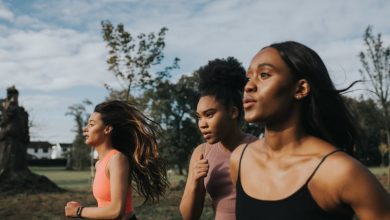 Women breathe while running through a sunny park at sunrise.