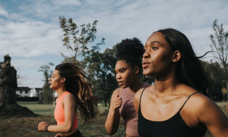 Women breathe while running through a sunny park at sunrise.