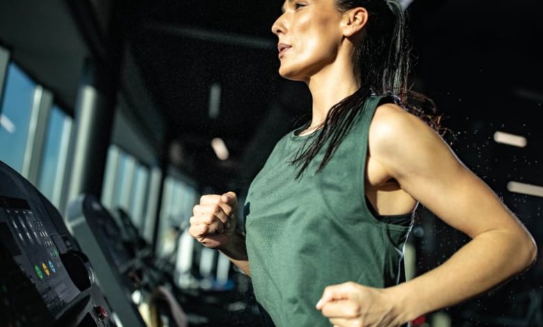 Young female athlete doing sprint interval training on a treadmill in a gym.