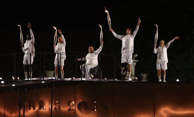 LtoR, France's paralympic torchbearers, Charles-Antoine Kaoukou, Nantenin Keita, Fabien Lamirault, Alexis Hanquinquant and Elodie Lorandi wave as they hold the flame as the Paris 2024 Paralympic Games cauldron, with the Olympic flame lit, lifts off while