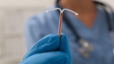 Doctor holding an IUD against a blurred background.