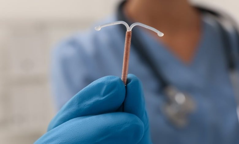 Doctor holding an IUD against a blurred background.