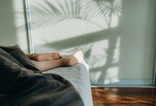 Woman sleeping in bed with feet and legs sticking out from underneath the blanket.