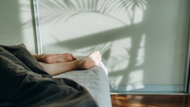 Woman sleeping in bed with feet and legs sticking out from underneath the blanket.
