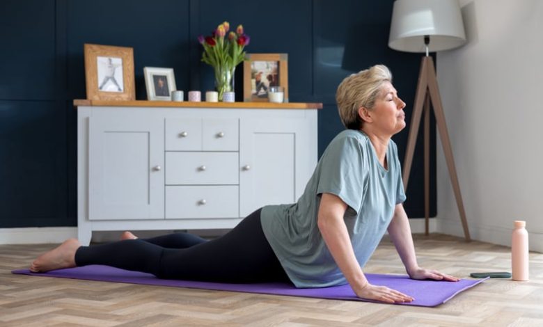 Woman living with breast cancer doing a cobra position on a purple yoga mat. Exercises after mastectomy.