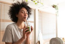 Woman drinking green smoothie with straw.