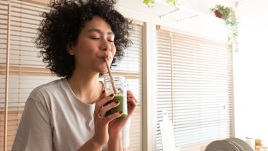 Woman drinking green smoothie with straw.
