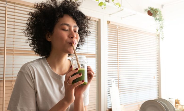 Woman drinking green smoothie with straw.